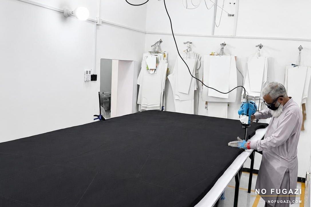 Fabric being cut to pattern on the cutting table at the NO FUGAZI facility