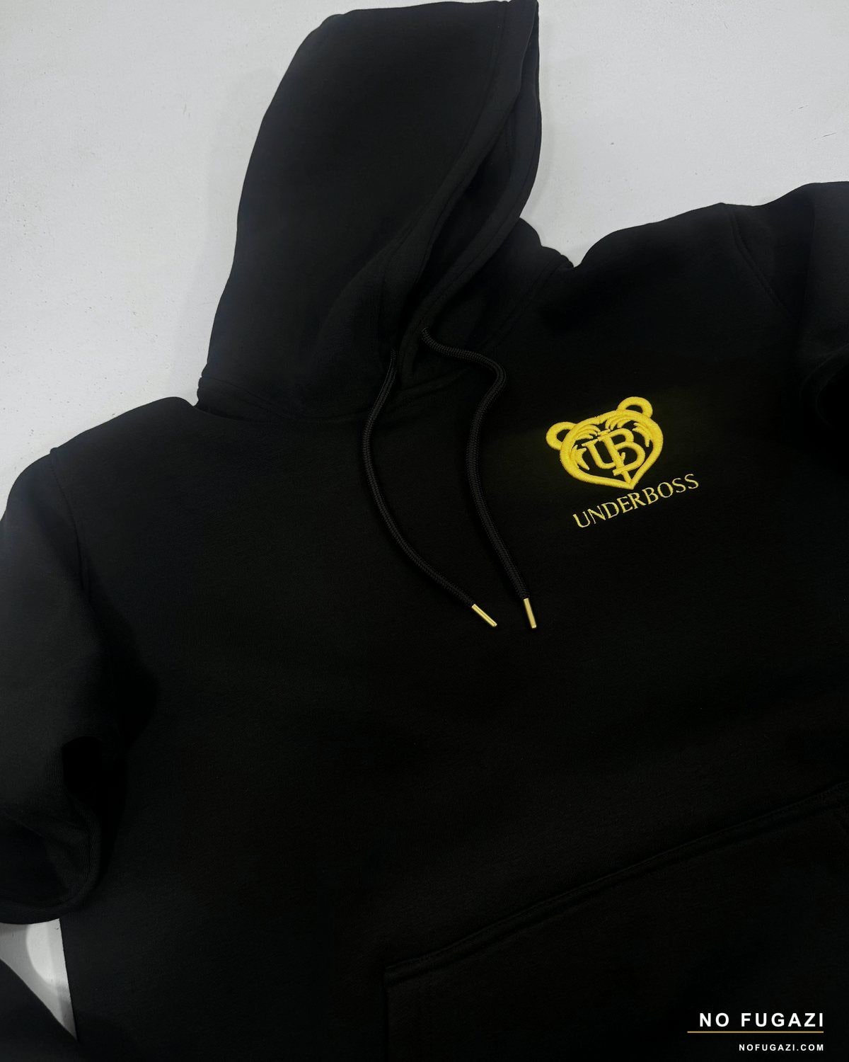 Gold embroidered chest logo on a black hoodie, with matching metal drawcord tips